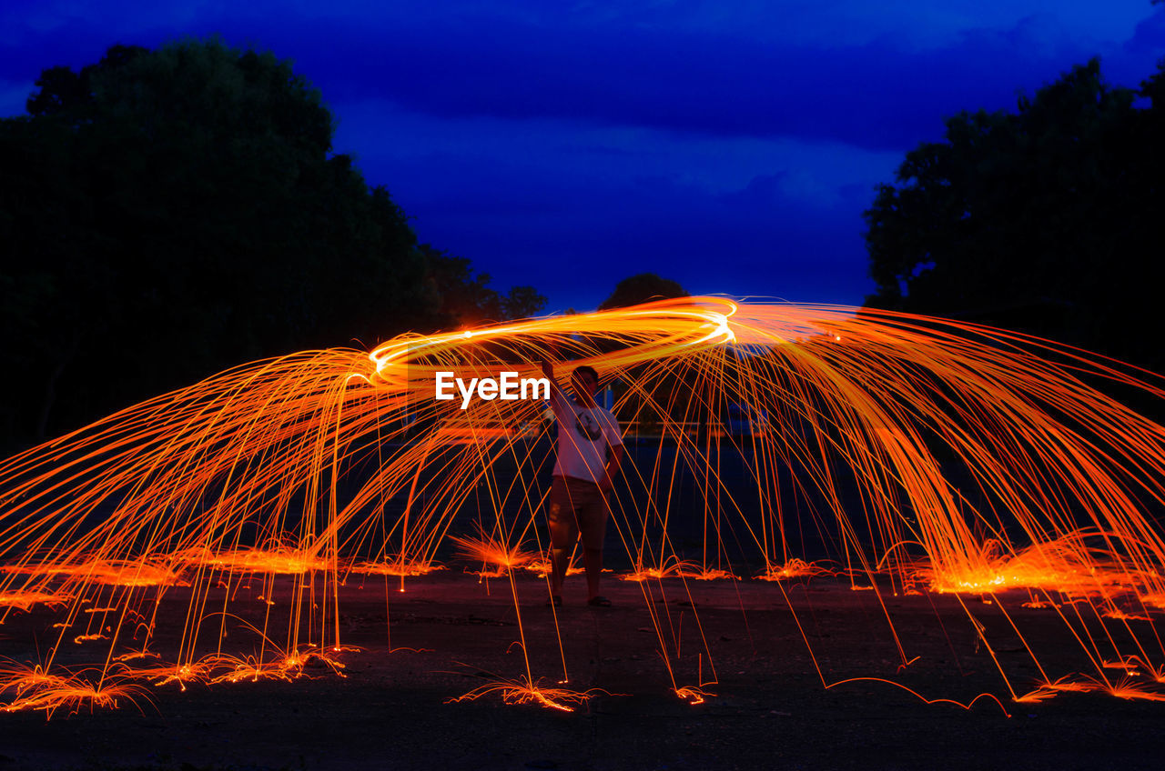 Man standing amidst wire wool at night