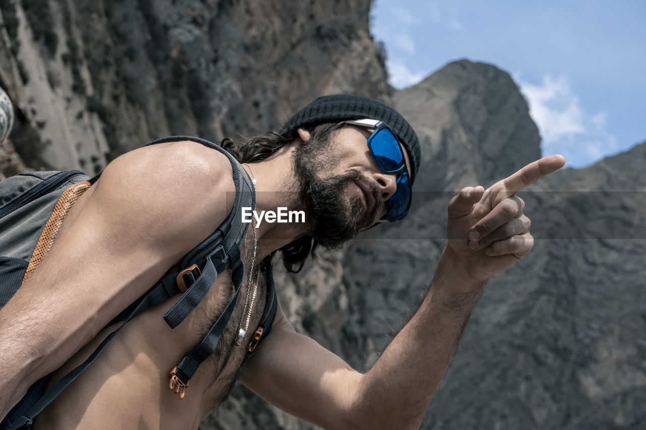 Shirtless man pointing against mountain