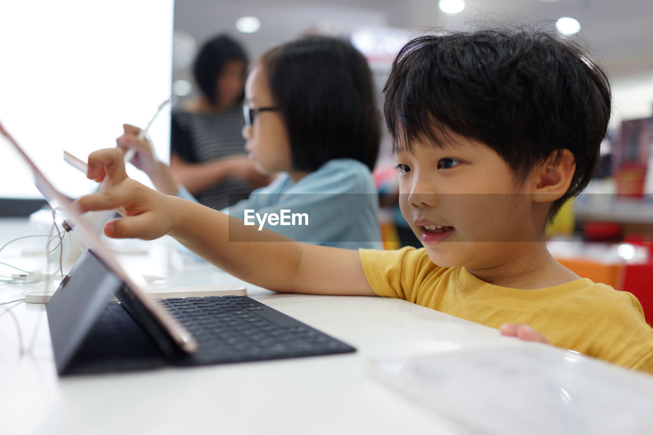 Cute siblings using laptop at table