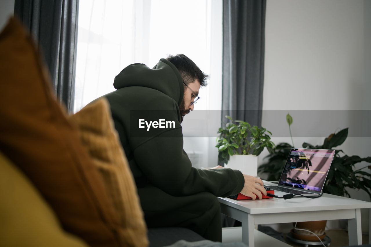 side view of woman using laptop while sitting at home