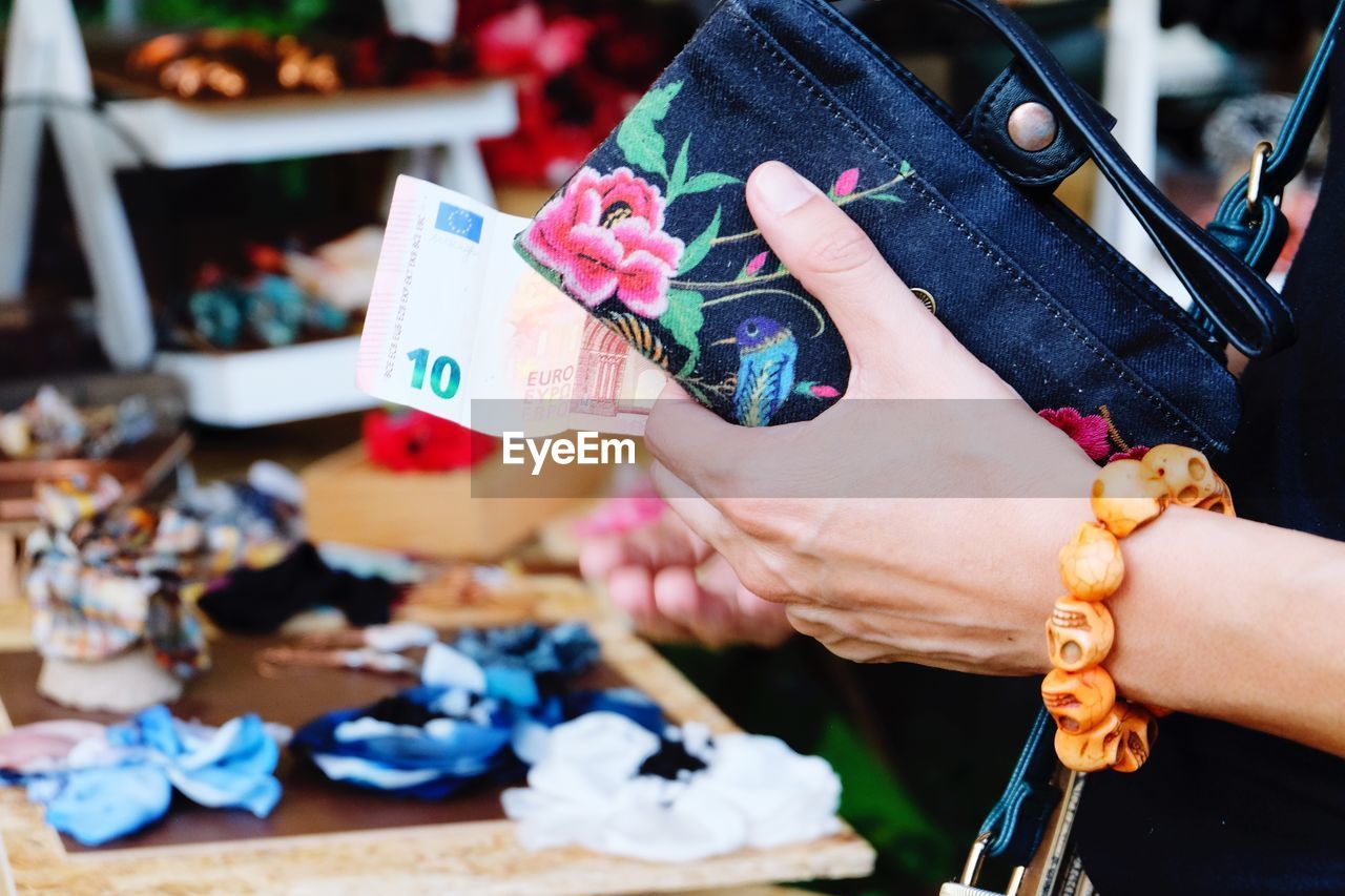 Cropped hand of woman holding purse and paper currency in market