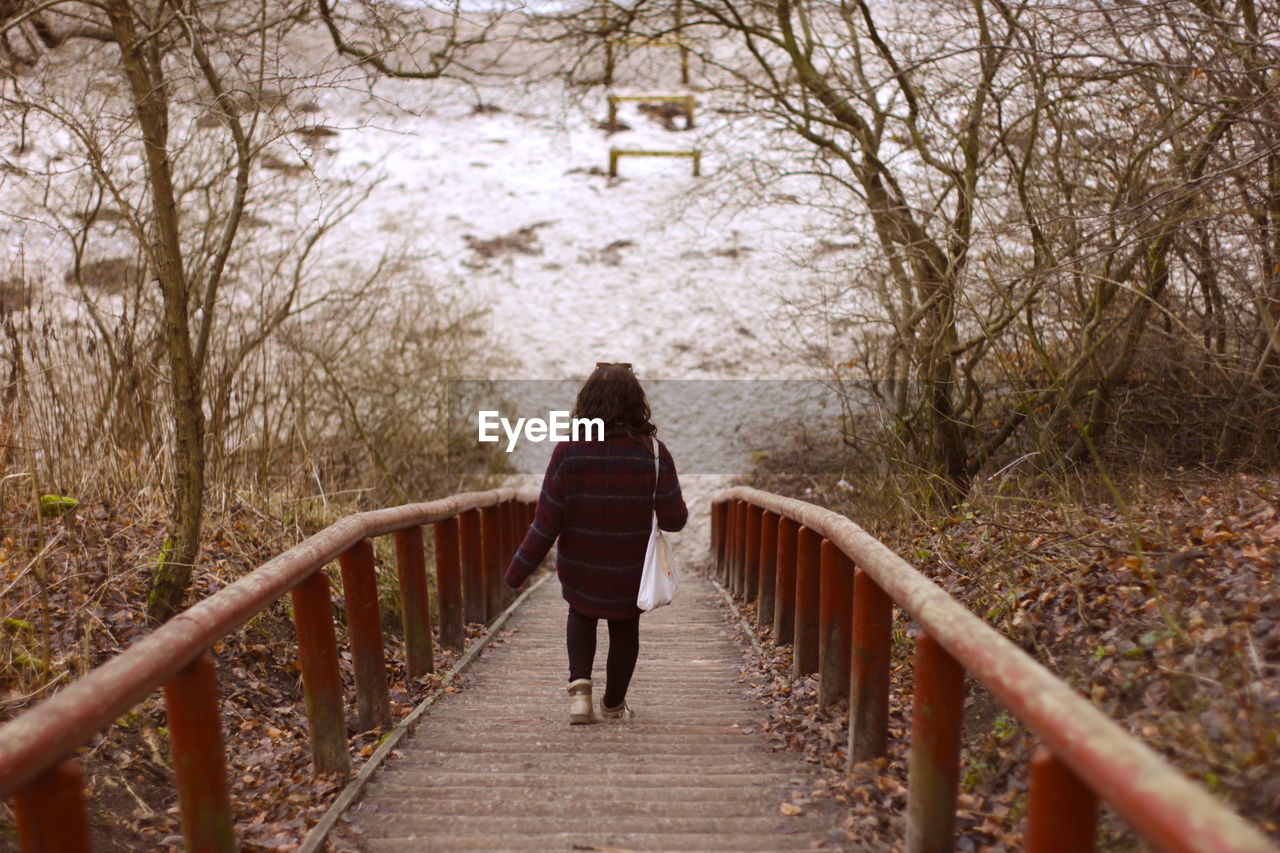 FULL LENGTH REAR VIEW OF WOMAN WALKING ON FOOTBRIDGE