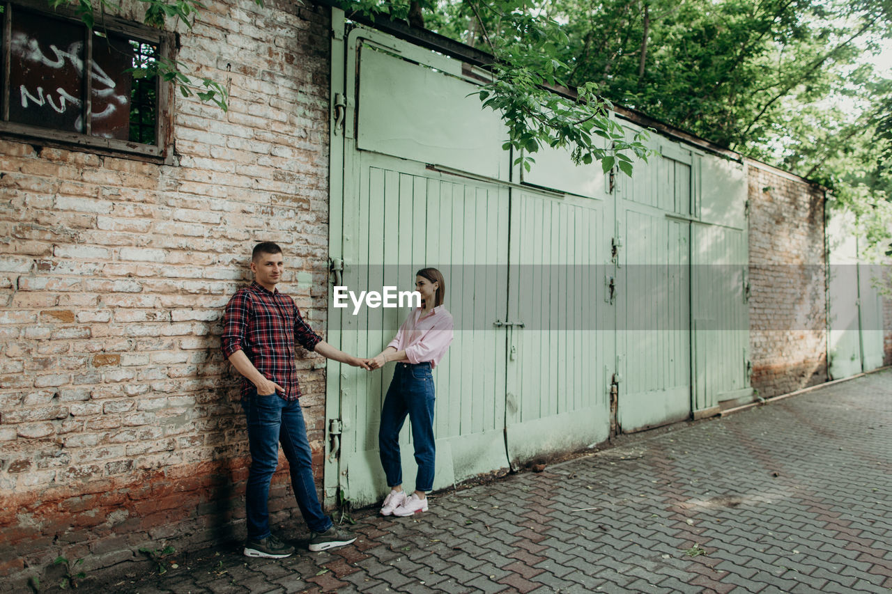 Couple holding hands while standing against wall