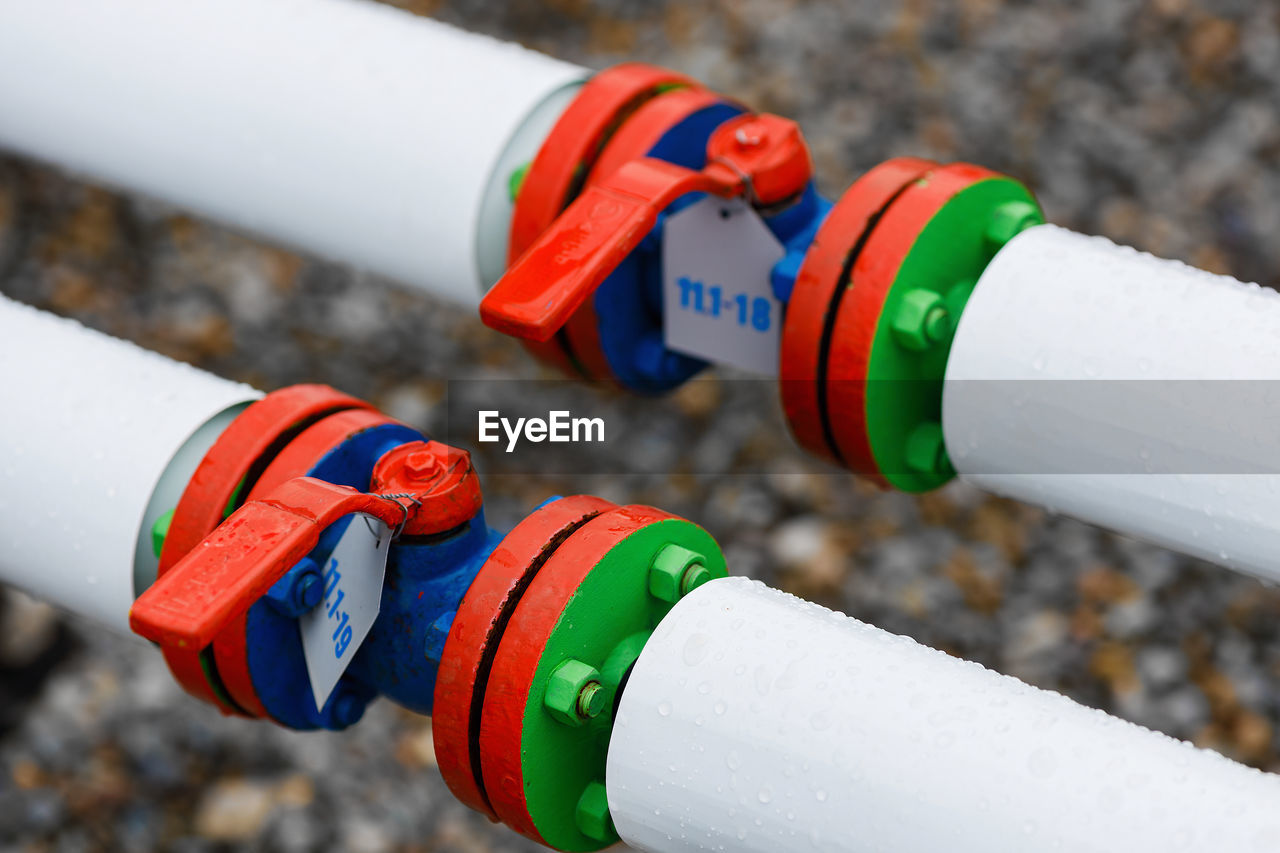 CLOSE-UP OF MULTI COLORED PIPES ON LAND