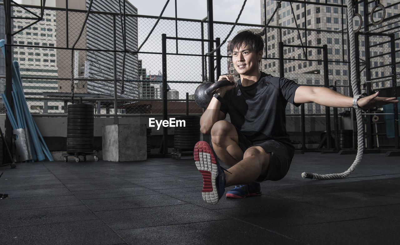 Man training with kettle bell at rooftop gym in bangkok