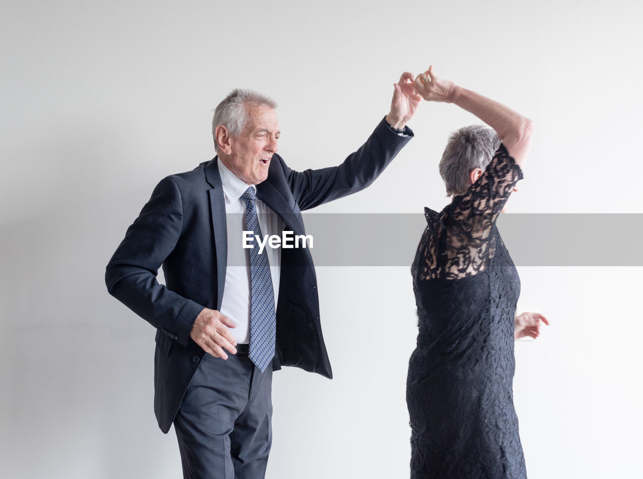 Senior couple dancing against white background