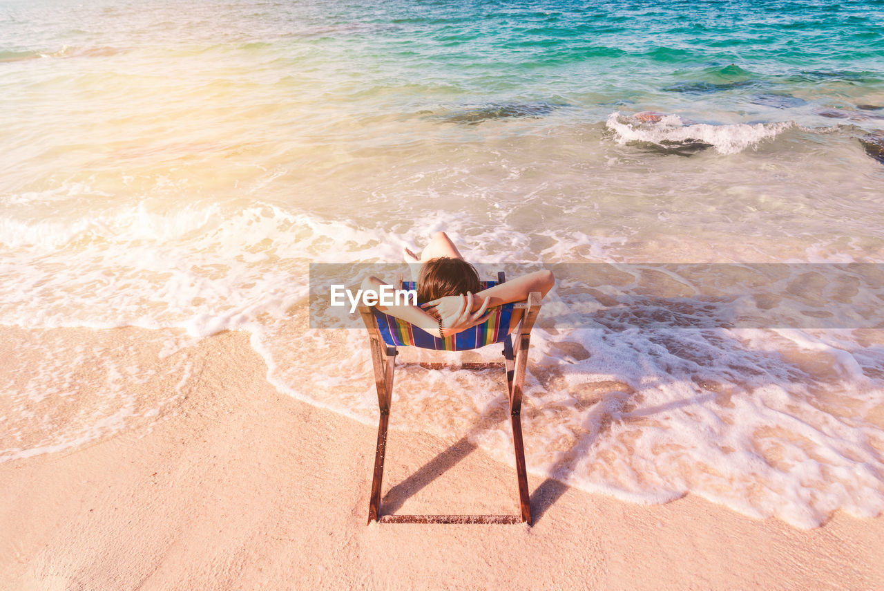 High angle view of woman sitting deck chair at beach