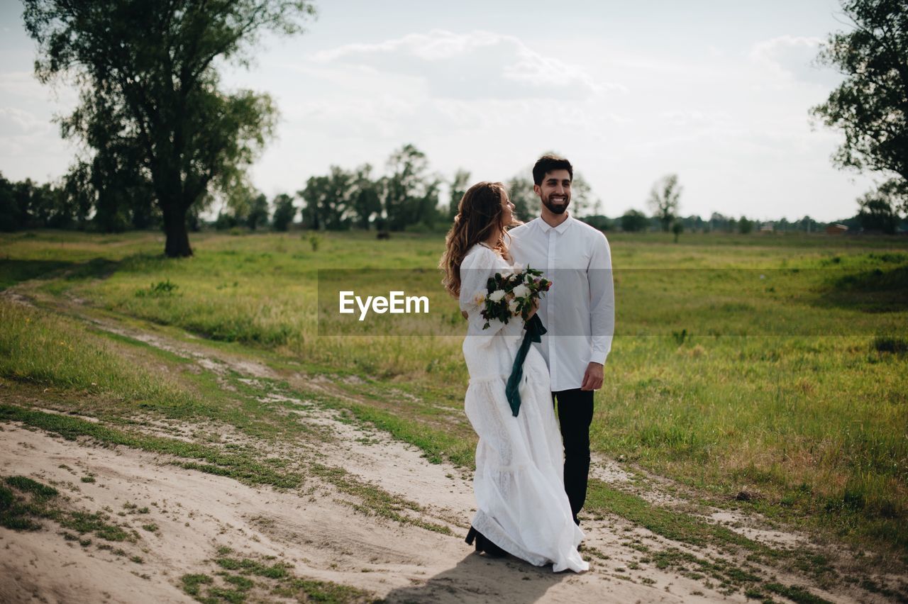 Bride and bridegroom standing on field