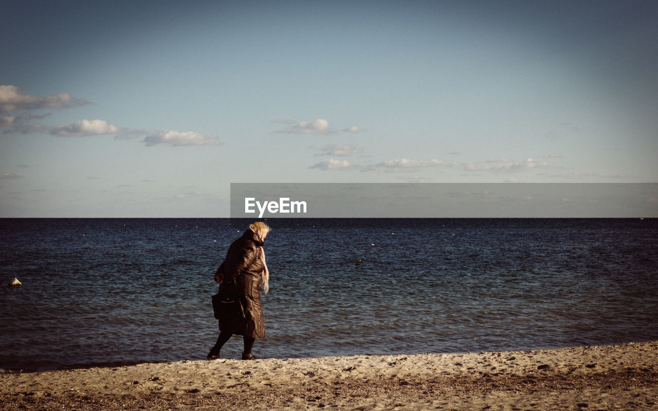 Woman walking on beach against sea