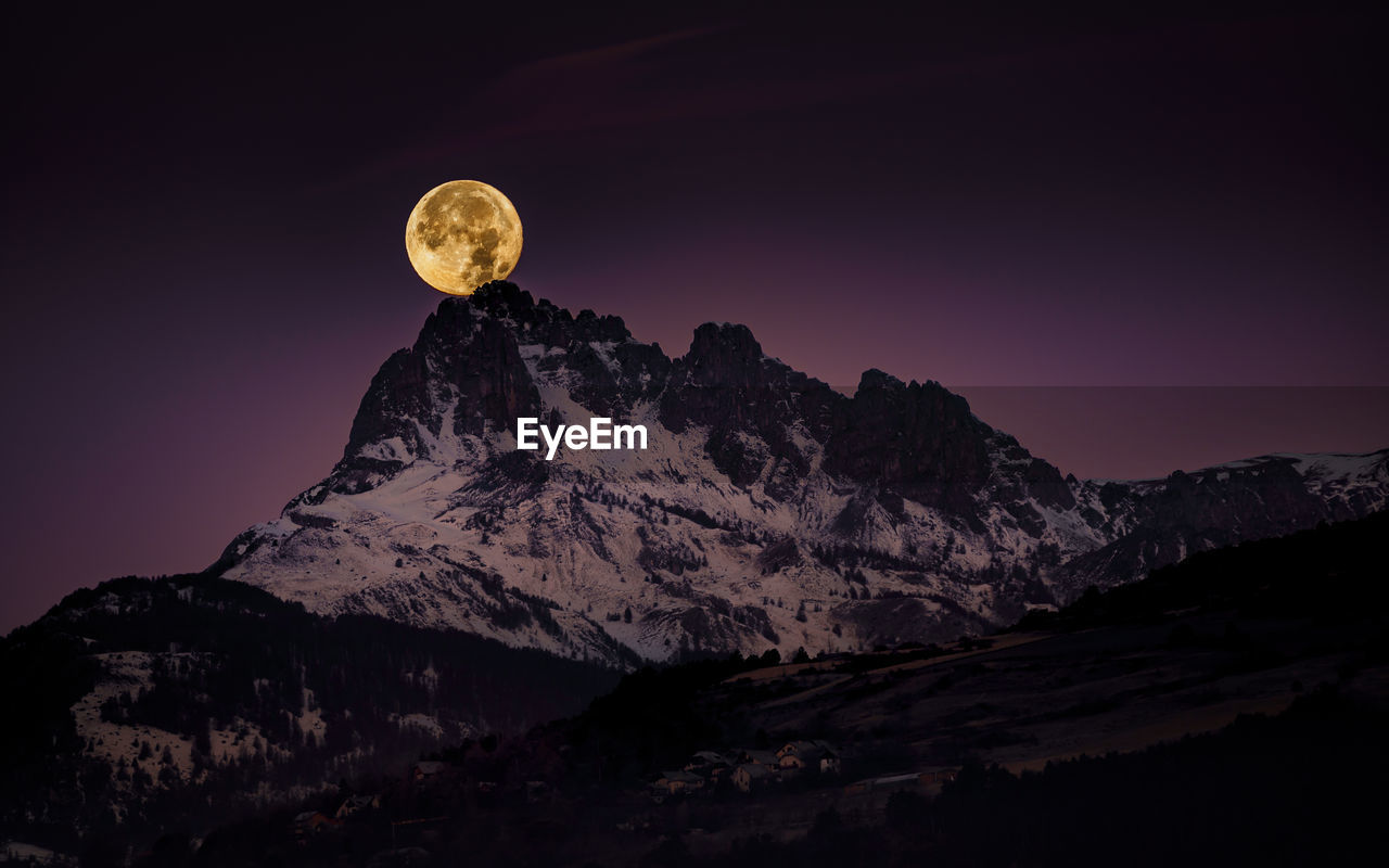 Scenic view of snowcapped mountains against sky at night and the big red full moon