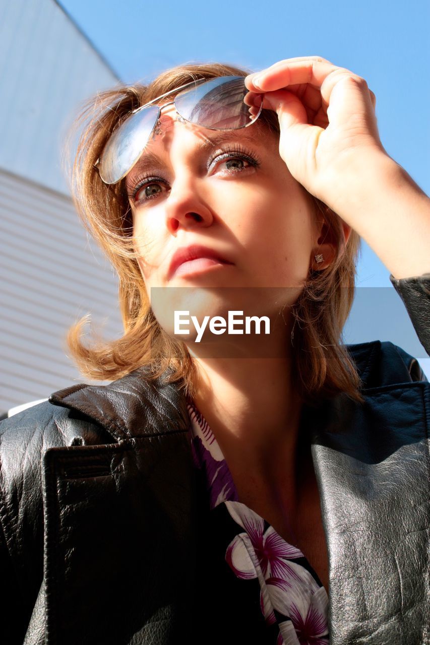 Woman holding sunglasses while looking away