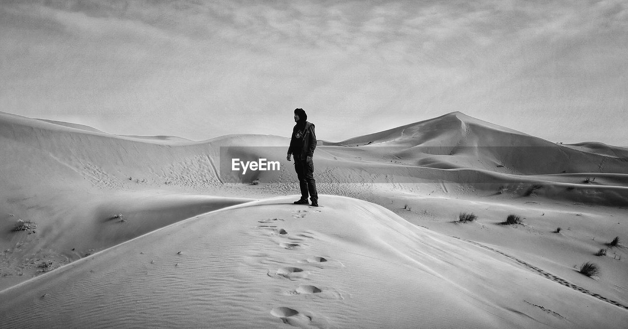 Rear view of man walking on sand dune