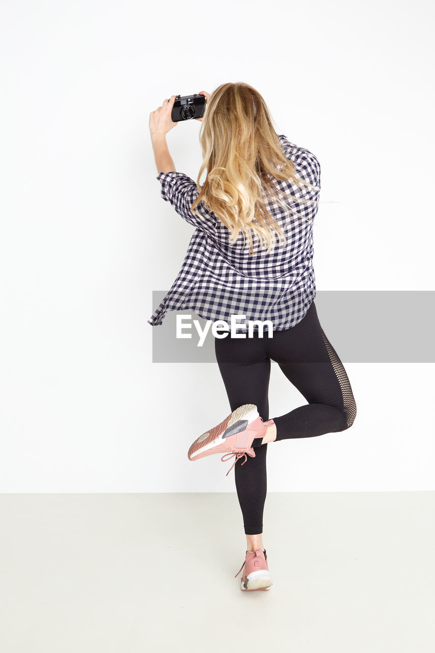 Full length of woman photographing against white background