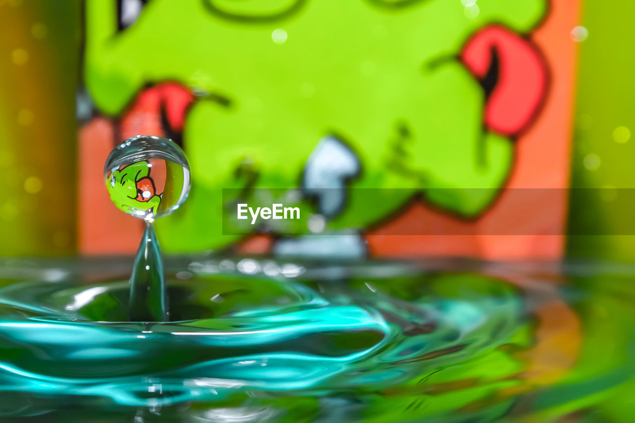 CLOSE-UP OF DROP FALLING ON WATER IN PLASTIC