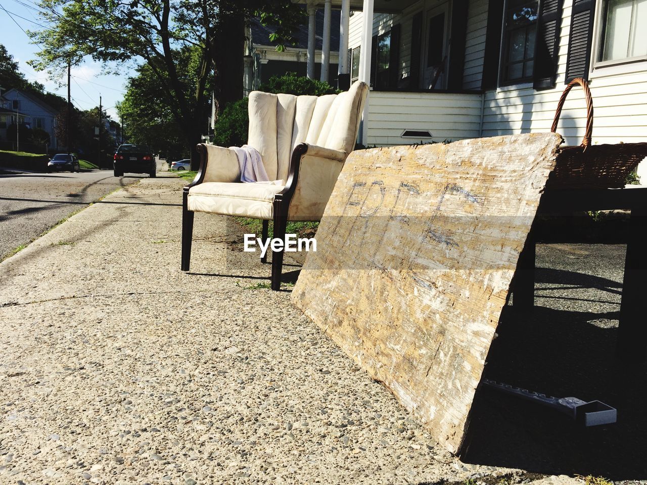 Empty chair by information sign on sidewalk by house