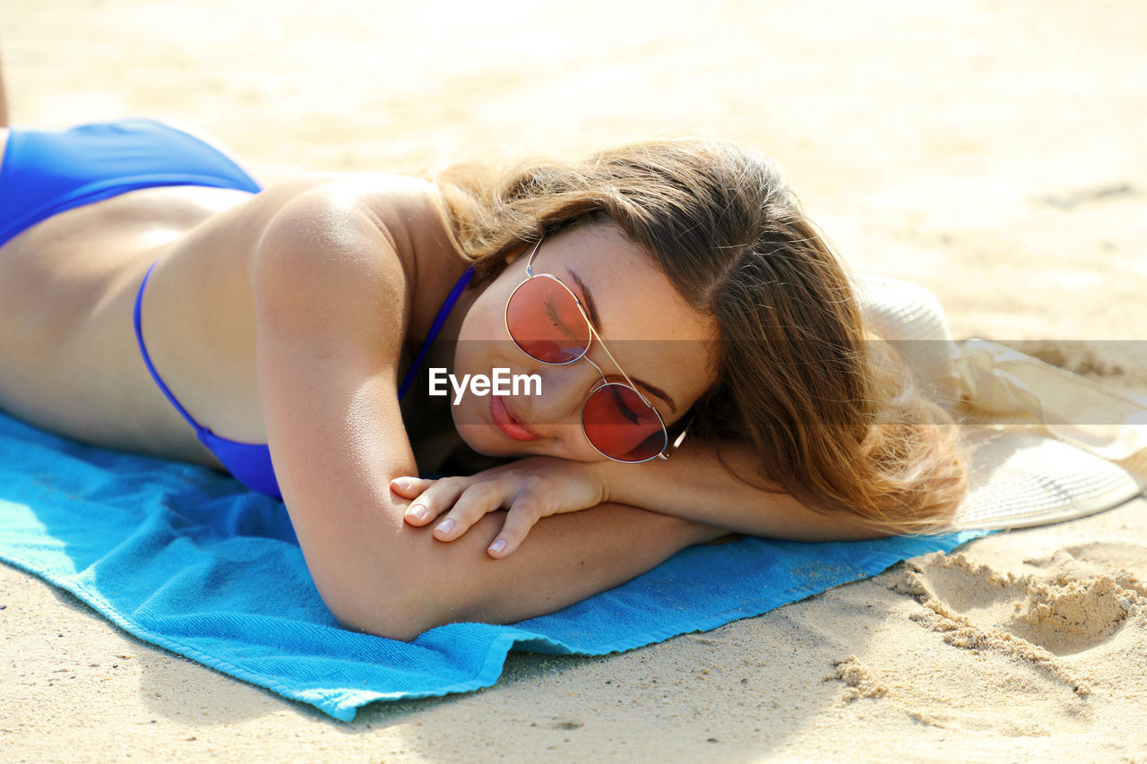 Beautiful woman wearing bikini lying relaxing on beach