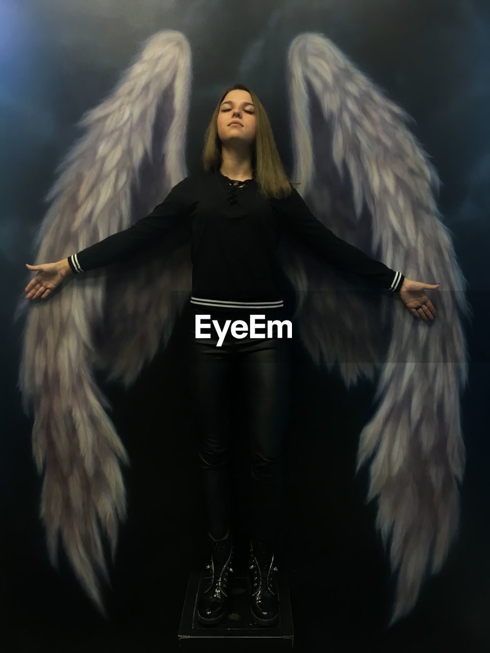 Young woman standing against angel wings