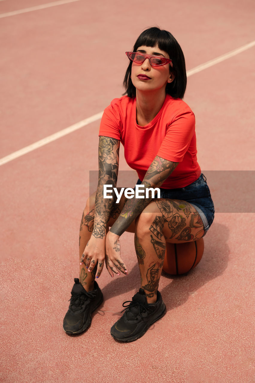 Caucasian girl with tattoos and short black hair on a sports court