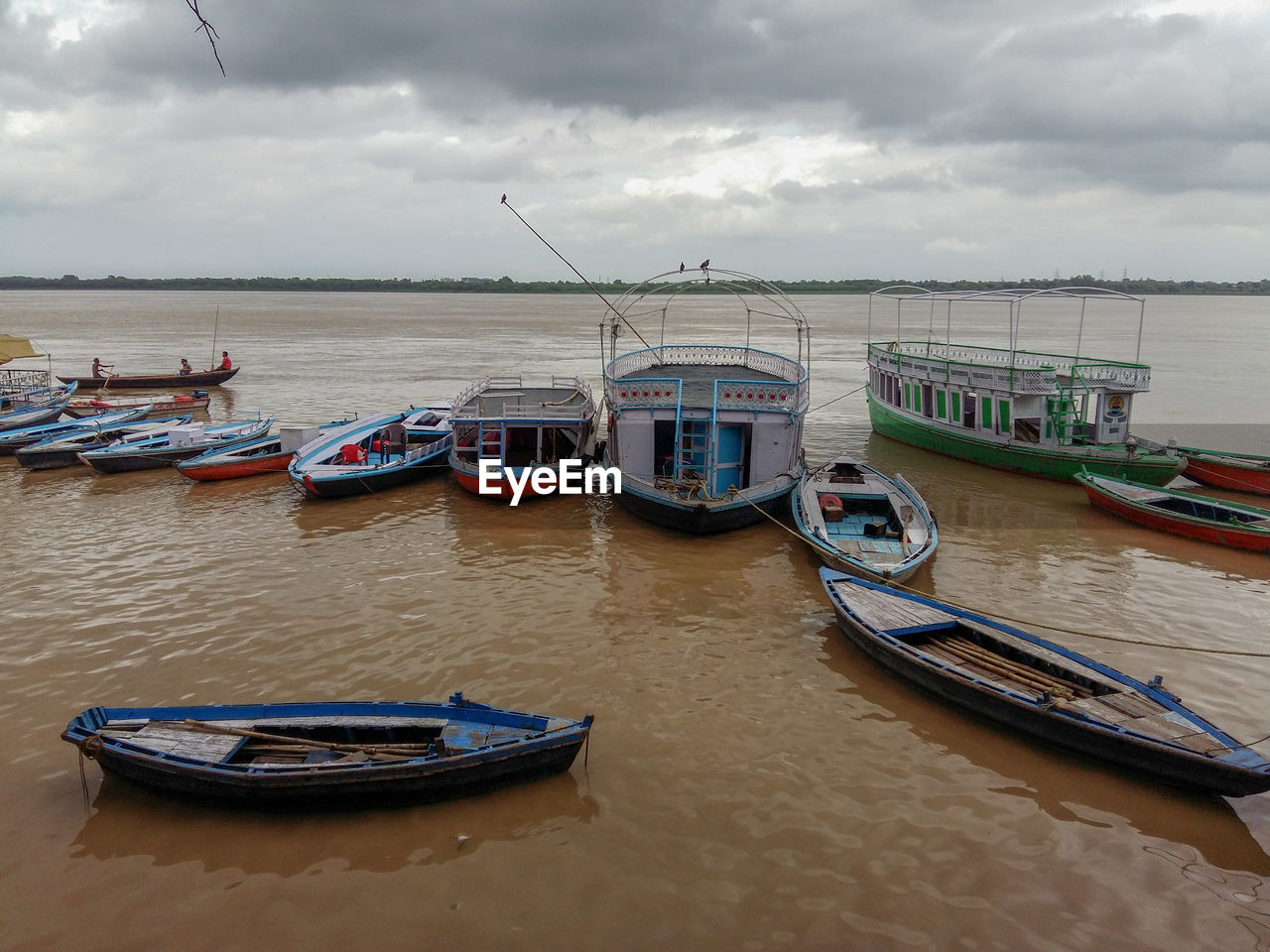 Boats moored in sea against cloudy sky