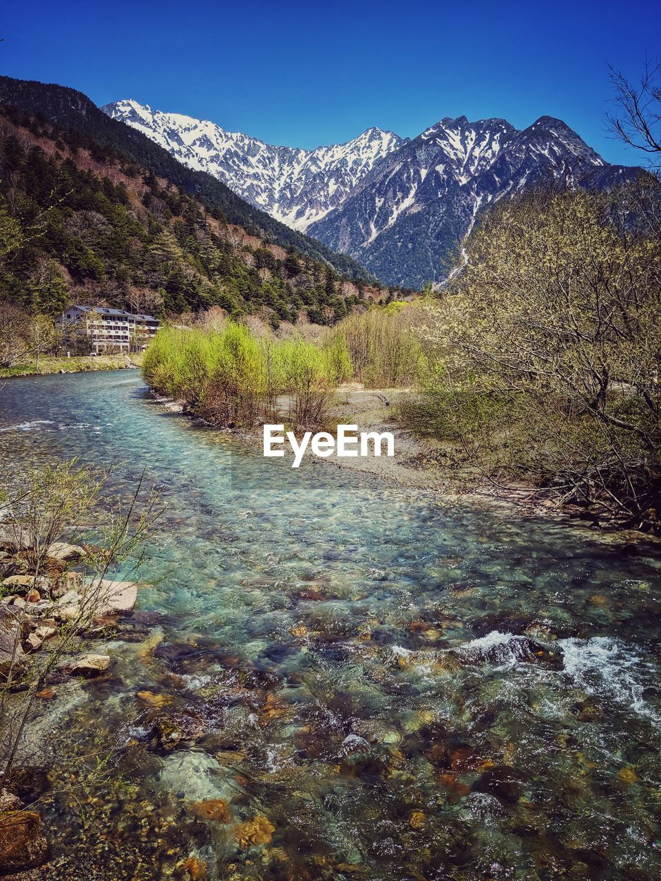 Scenic view of river amidst mountains against clear blue sky