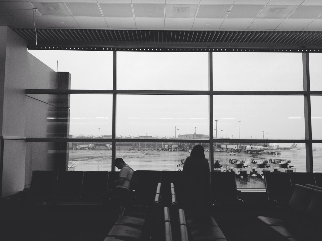 sitting, real people, two people, indoors, men, waiting, women, rear view, lifestyles, window, airport departure area, relaxation, built structure, leisure activity, day, airport, architecture, togetherness, sky, friendship, adult, people