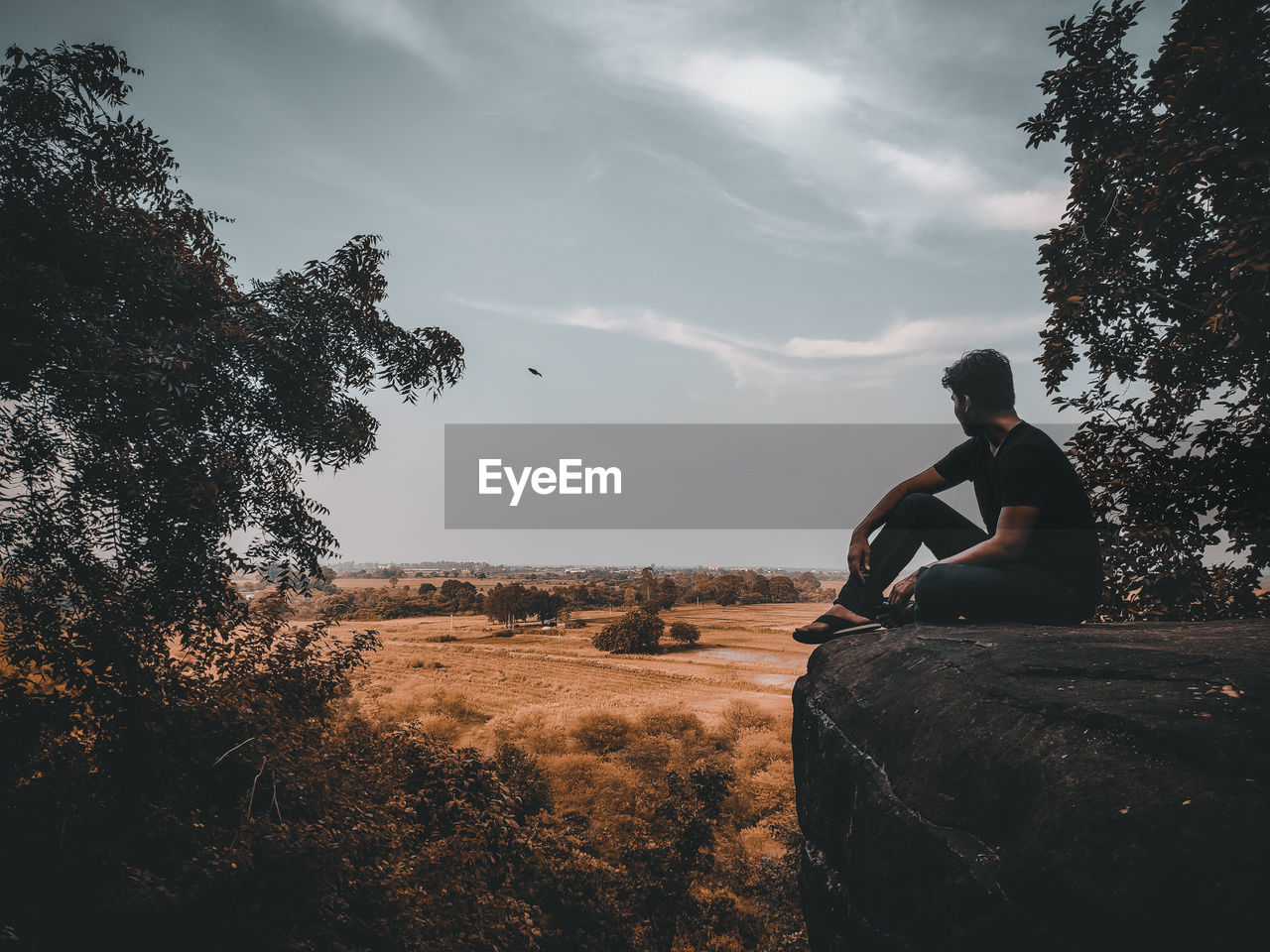 View from top of udiagiri caves. man sitting on a top of a high mountain looking at a beautiful sky