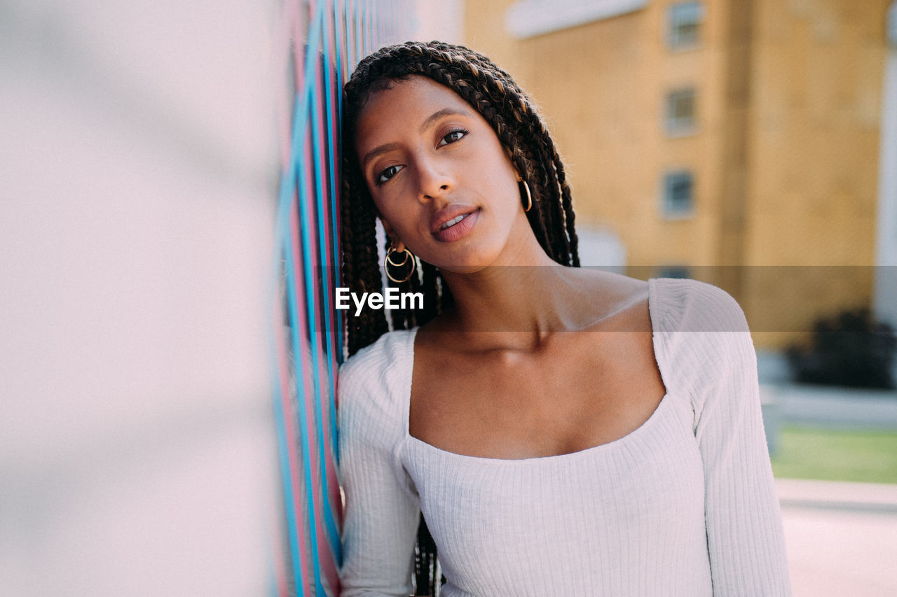 Portrait of smiling young woman leaning on wall