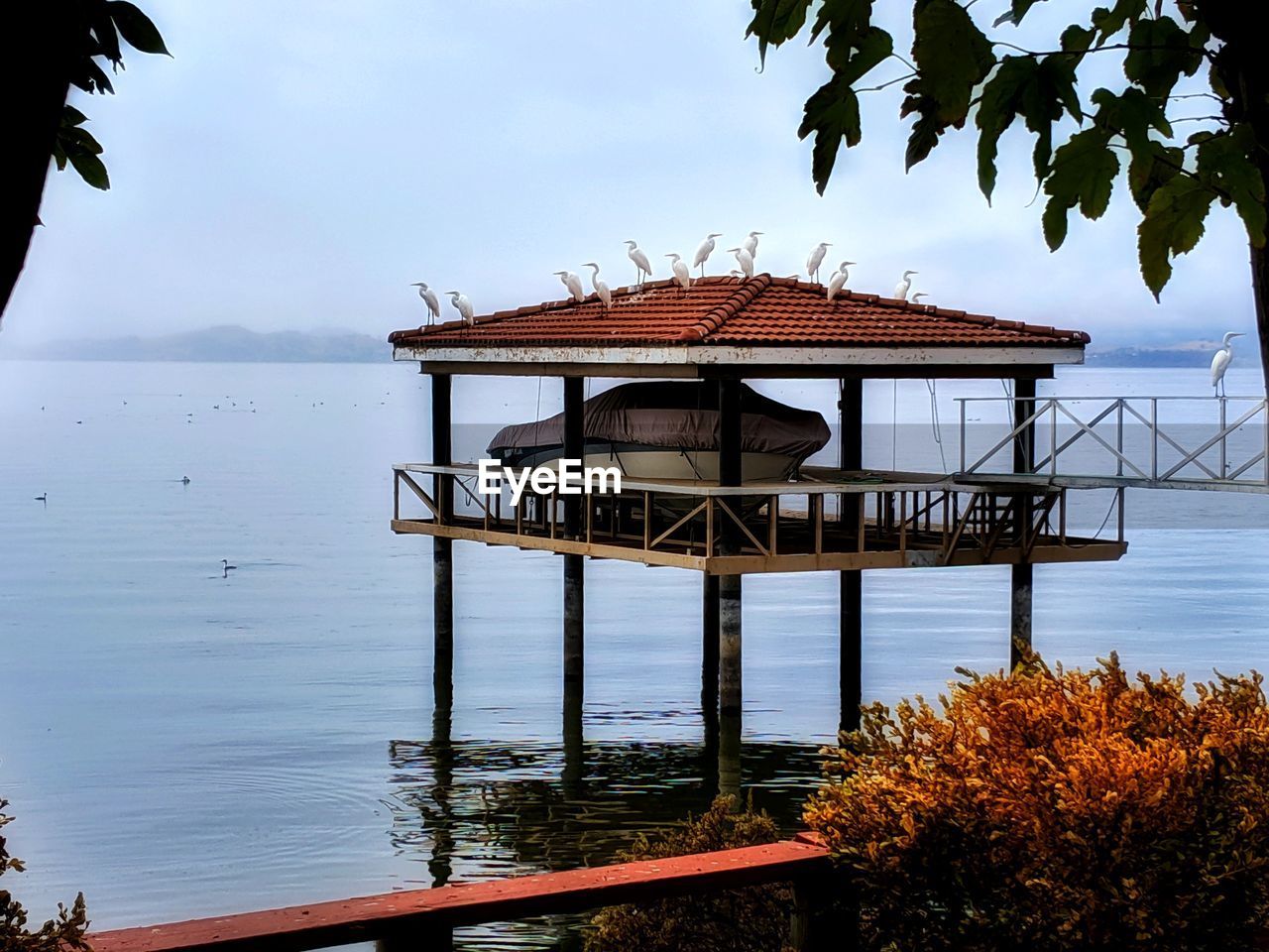 Boathouse in lake against sky