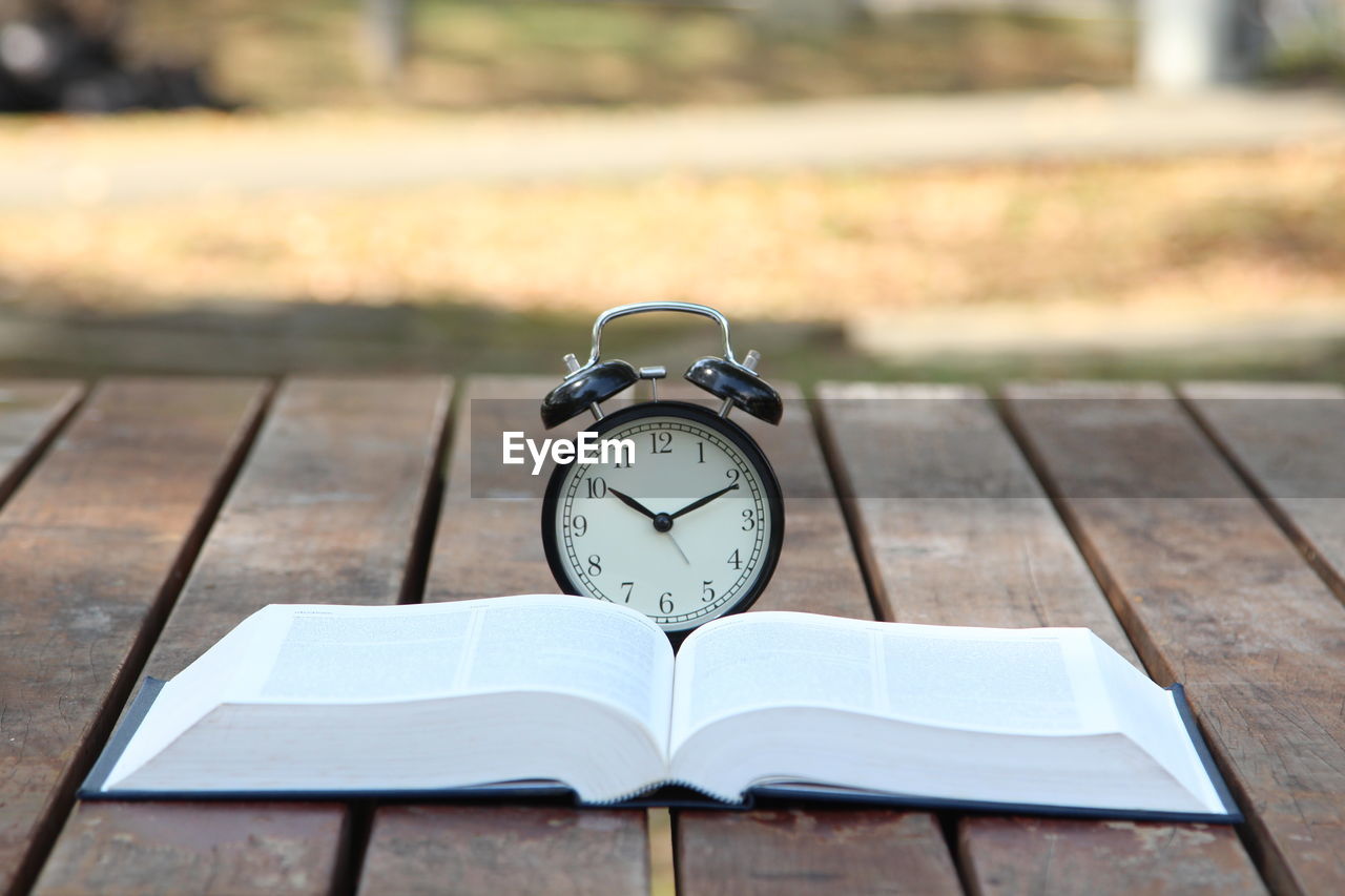 Close-up of alarm clock on book at table