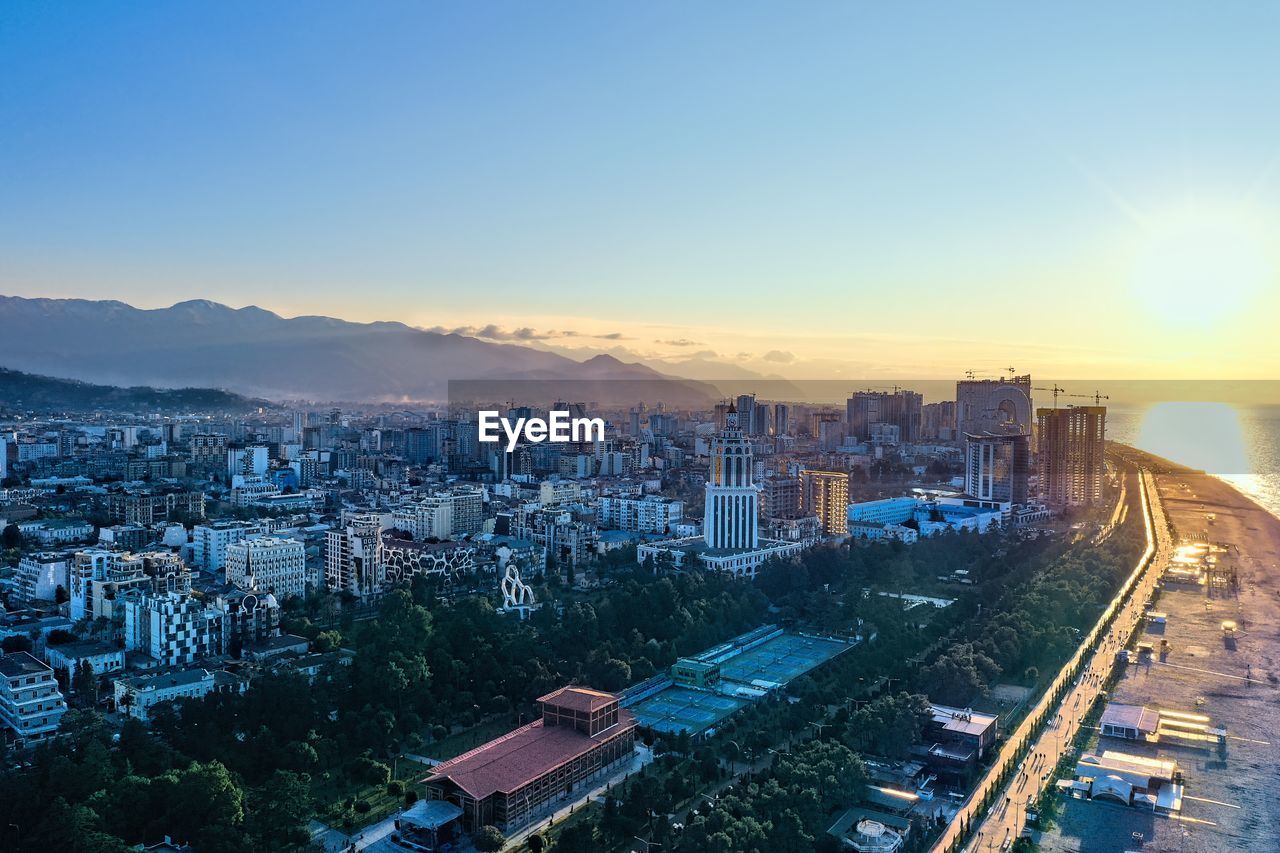 HIGH ANGLE VIEW OF BUILDINGS IN CITY AT SUNSET