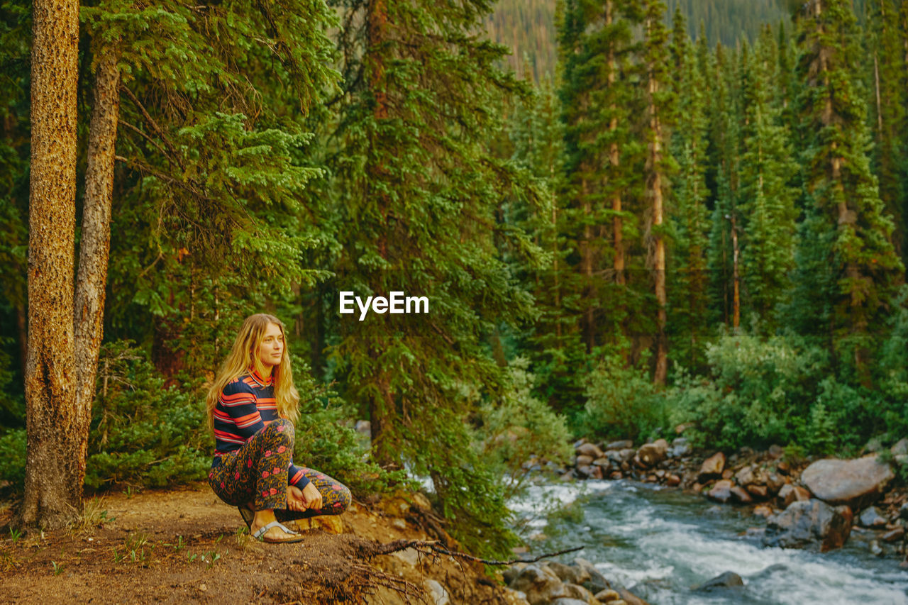 Young woman sitting on riverbed during sunset sunset near aspen