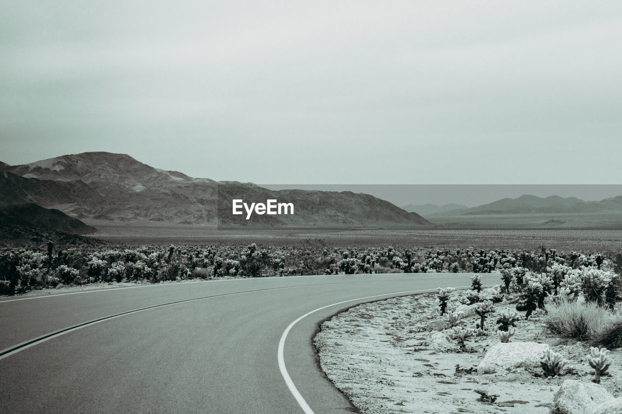 Road leading towards mountains against sky