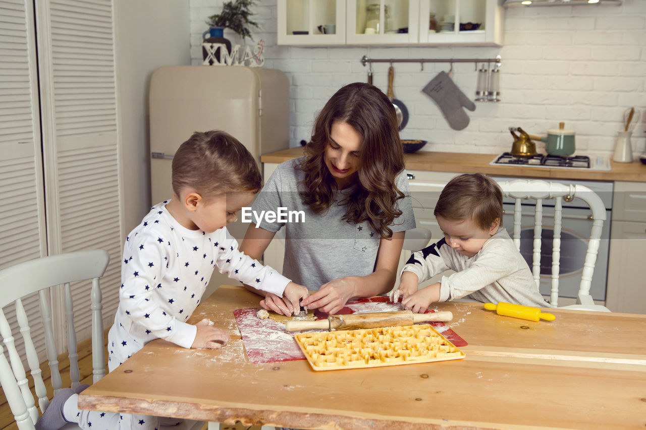 Mother with children sons making cookies in the kitchen