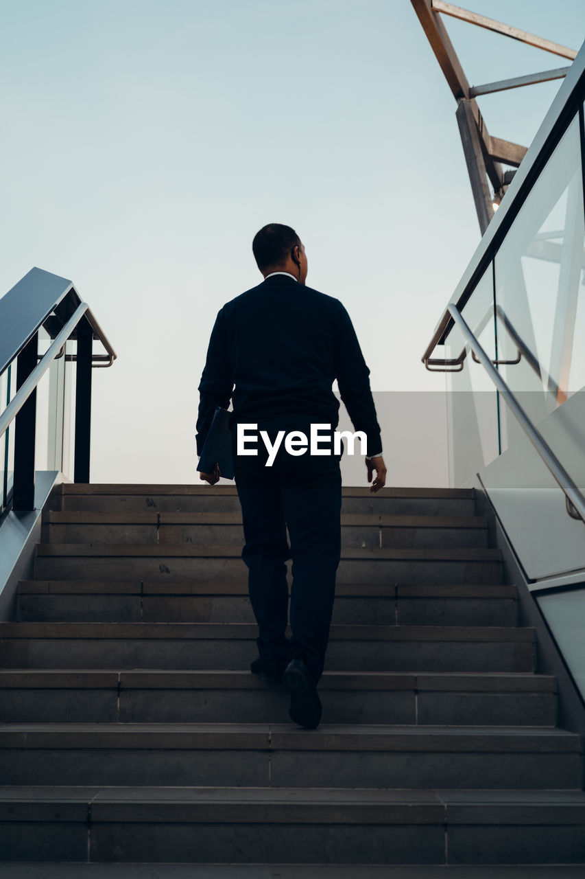 Rear view of man on staircase against sky