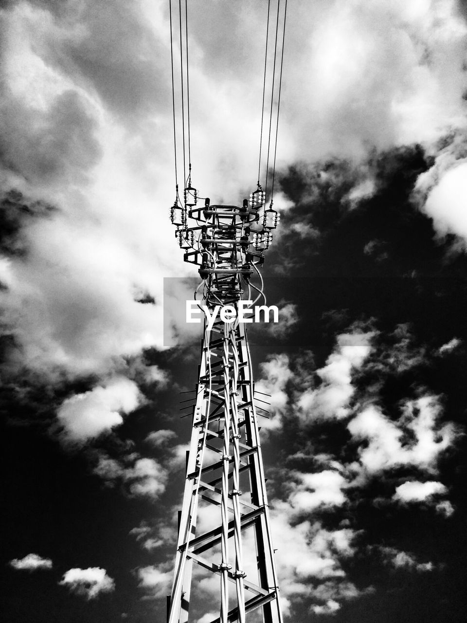 Low angle view of electricity pylon against cloudy sky