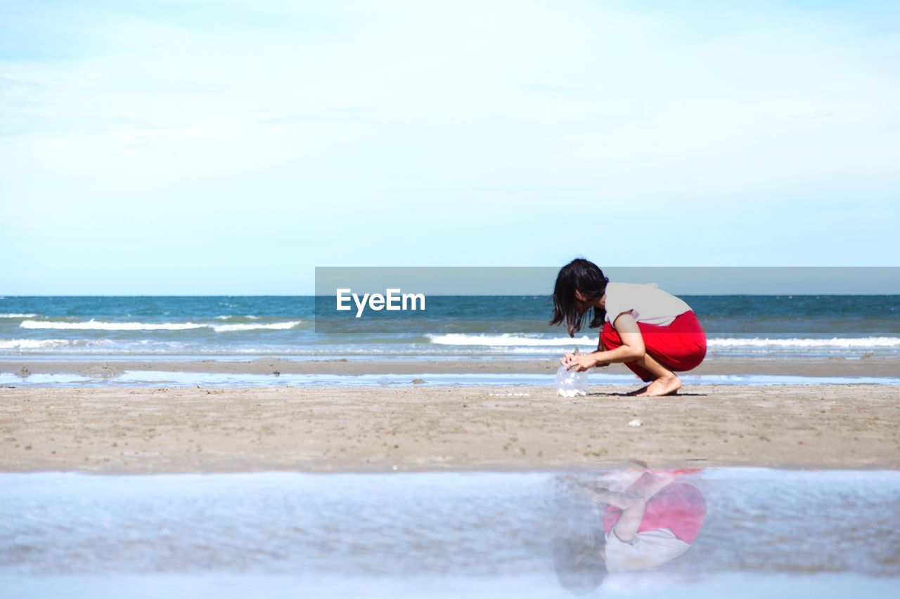 Woman picking seashells at beach