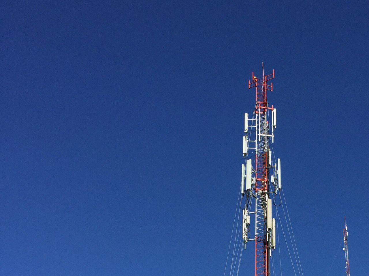 Low angle view of communications tower against clear blue sky