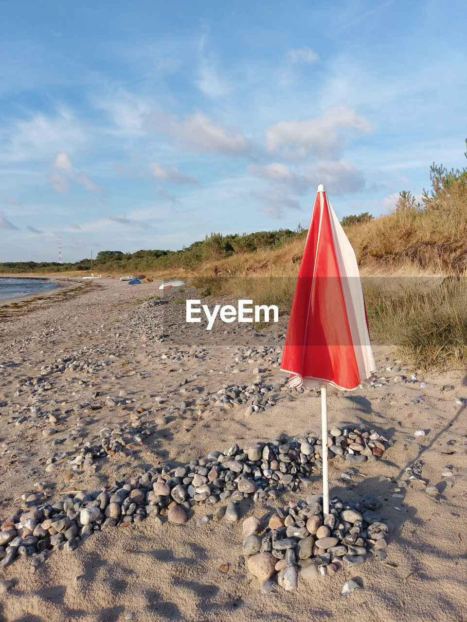 Folded red and white parasol on the emty morning beach of the baltic sea on rügen