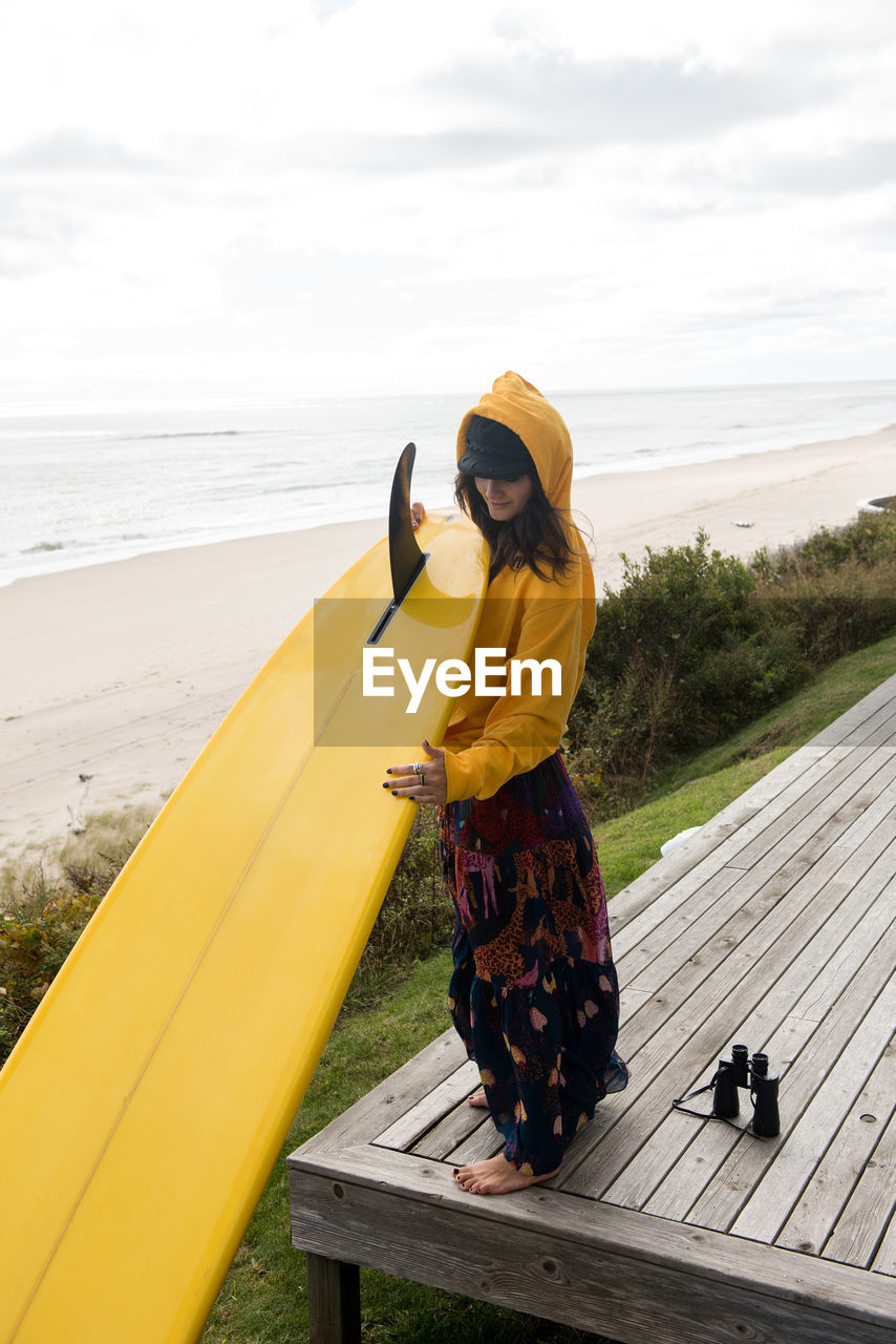 Female surfer prepares her surfboard for adventure