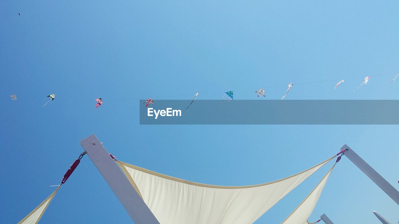 LOW ANGLE VIEW OF FLAGS HANGING AGAINST CLEAR BLUE SKY