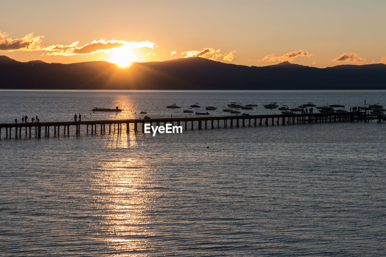 Pier over sea against sky during sunset