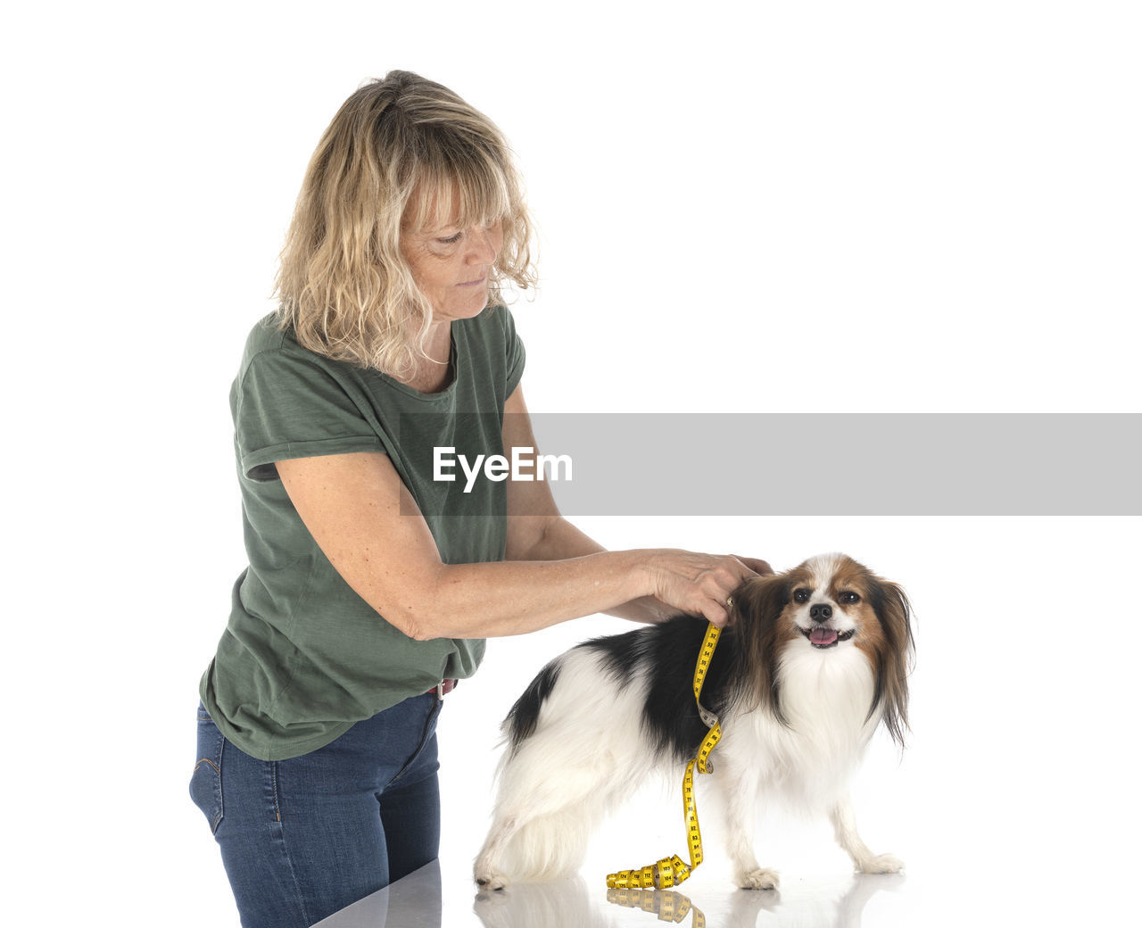 FULL LENGTH OF WOMAN WITH DOG AGAINST WHITE BACKGROUND ON STREET