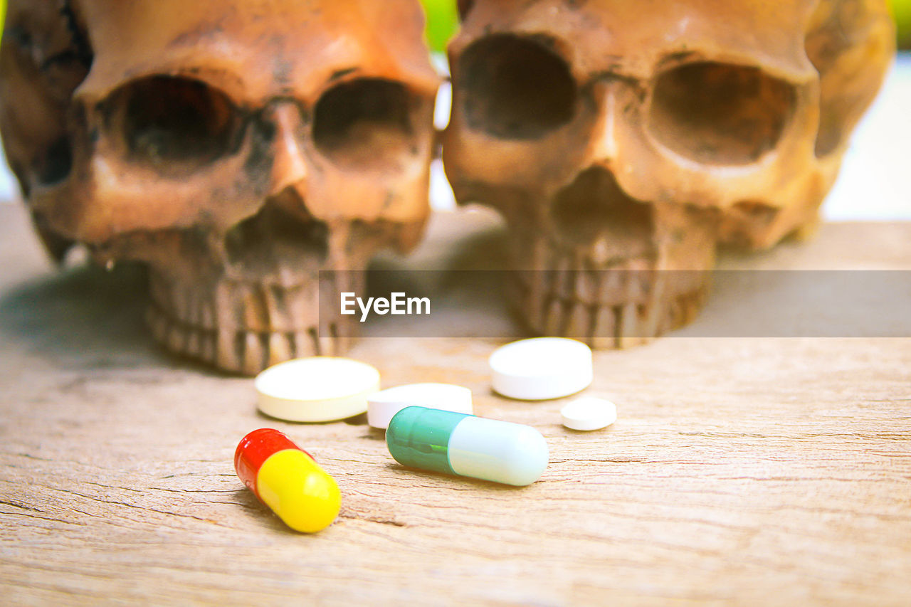 Close-up of human skull and pills on table