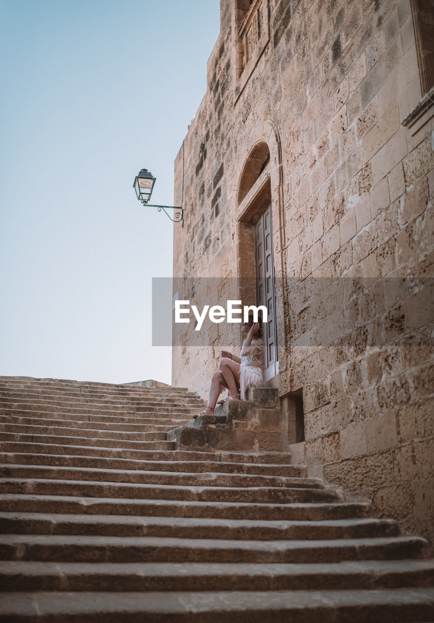 LOW ANGLE VIEW OF PERSON ON STAIRCASE OF BUILDING