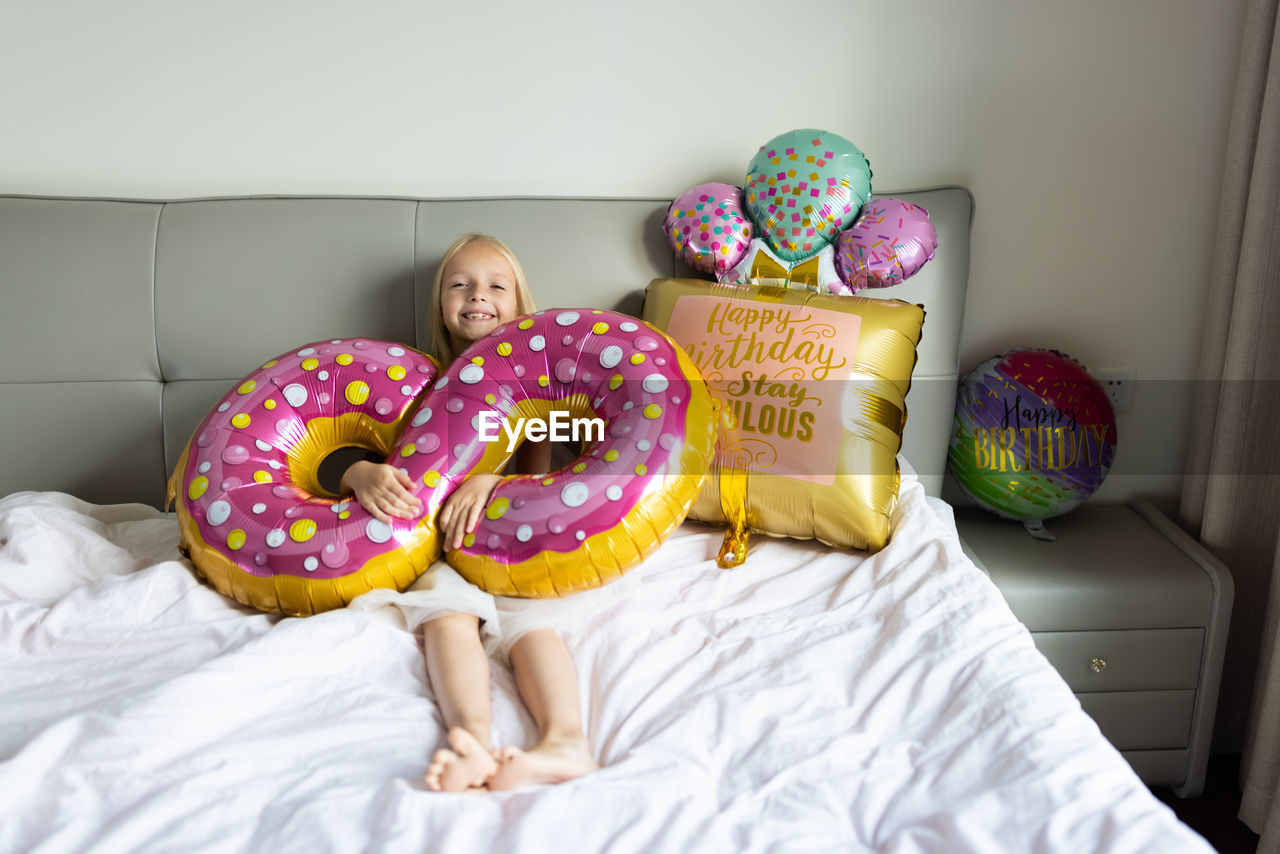 Portrait of girl with balloon lying on bed at home