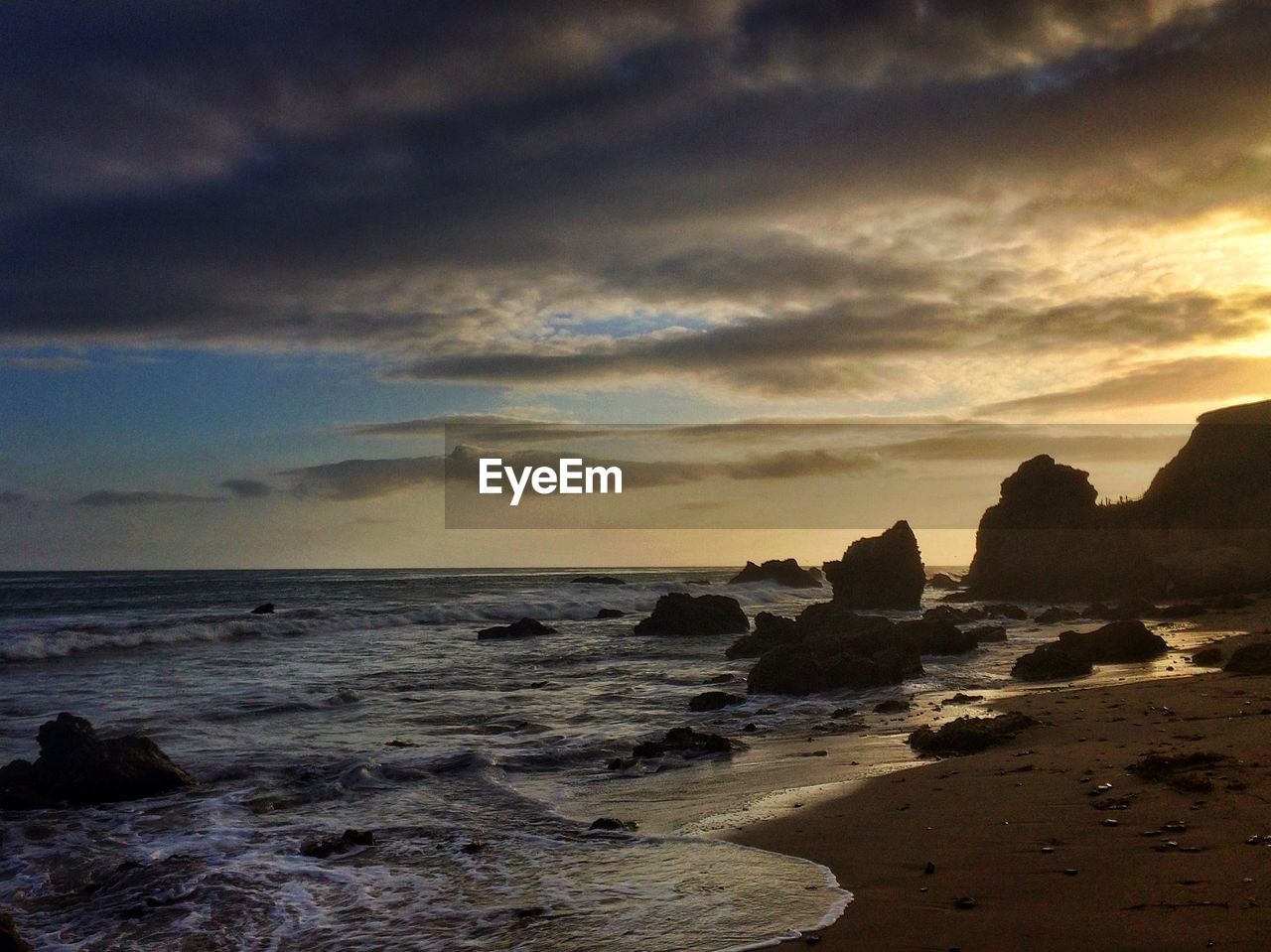 View of surf and tide on beach at sunset