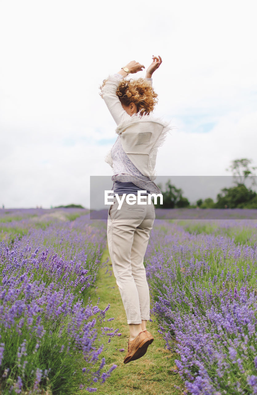 Full length of woman jumping on lavender field
