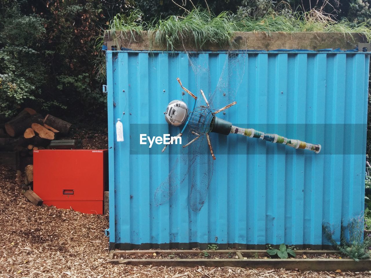 Artificial dragonfly made of waste material stuck on corrugated structure at yard