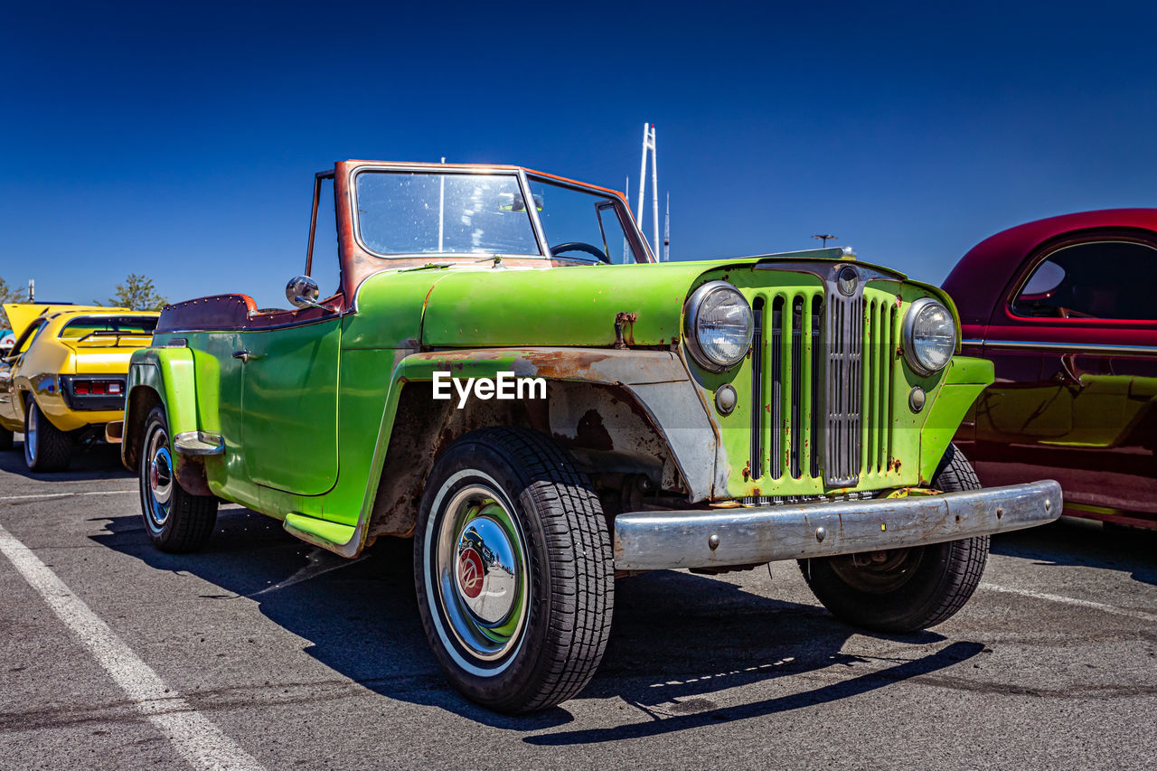 transportation, car, mode of transportation, vehicle, motor vehicle, land vehicle, antique car, blue, truck, sky, clear sky, sunny, road, city, retro styled, travel, sunlight, commercial land vehicle, street, nature, vintage car, pickup truck, wheel, day, architecture, jeep, off-road vehicle