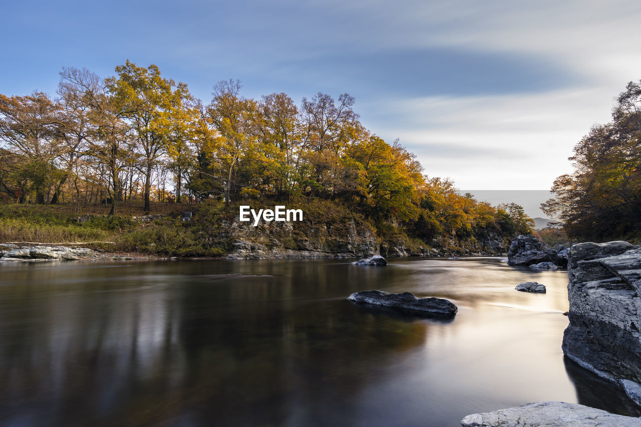 River flowing through rocks against sky